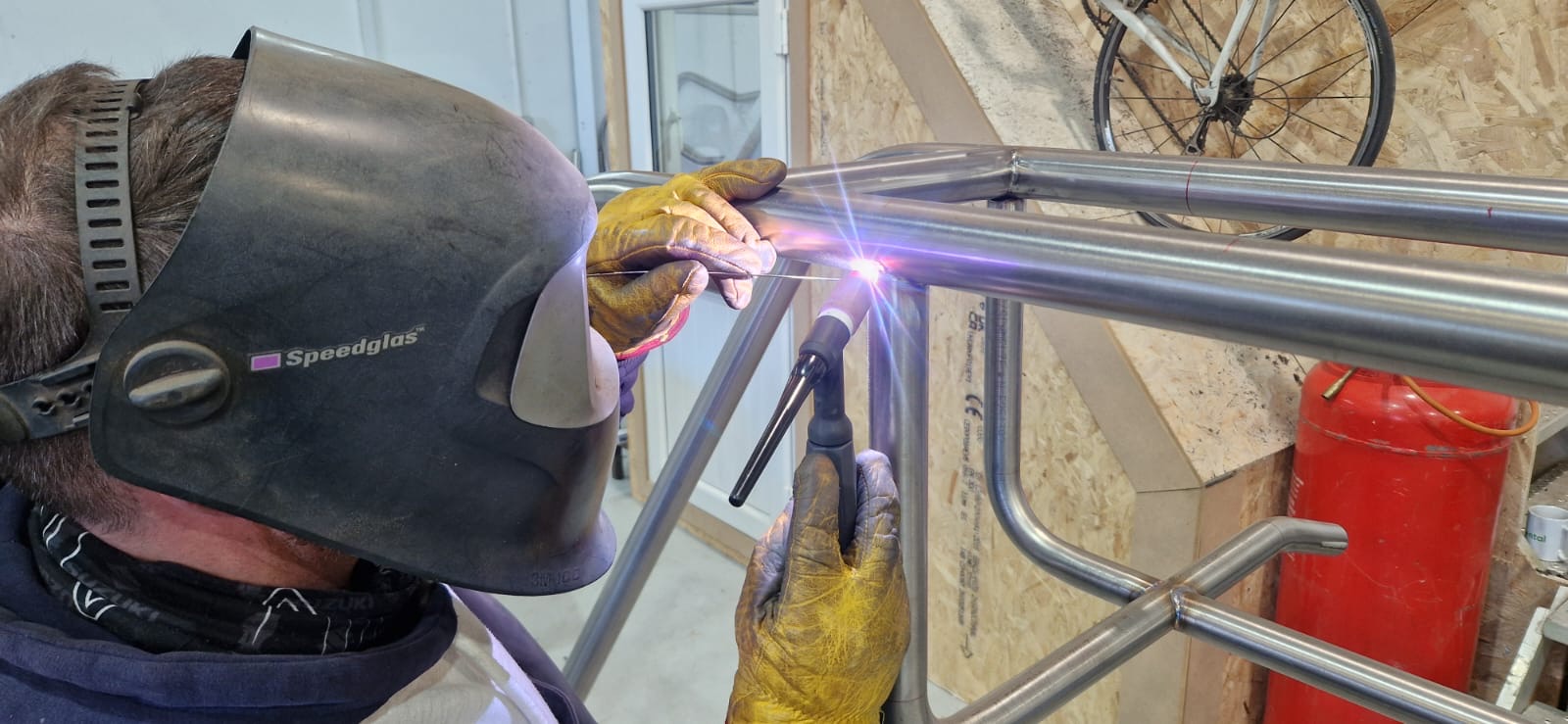 Welder TIG-welding stainless steel tube framework in the NESS Marine workshop using a Speedglas welding mask