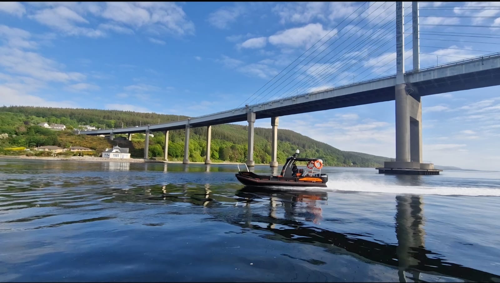 NESS Marine workboat on speed trial passing under a cable-stayed bridge on a Scottish firth