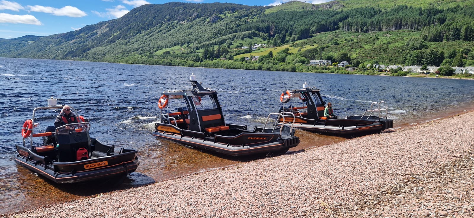 Three NESS Marine workboats, Black Hawk, Phoenix and Stormrider, beached on the shingle shore of Loch Ness